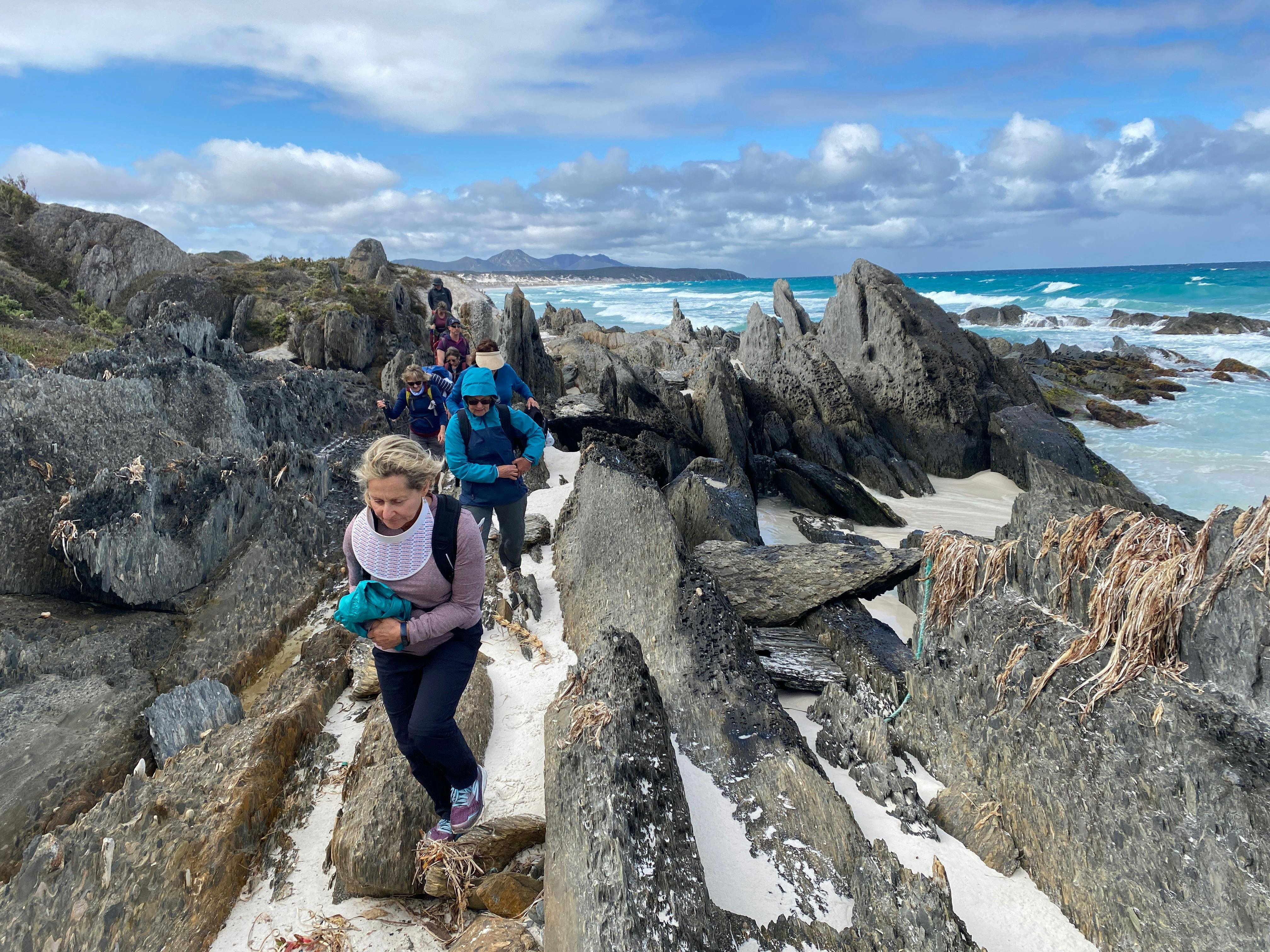 women walking along a pristine beach - turquoise sea in background.