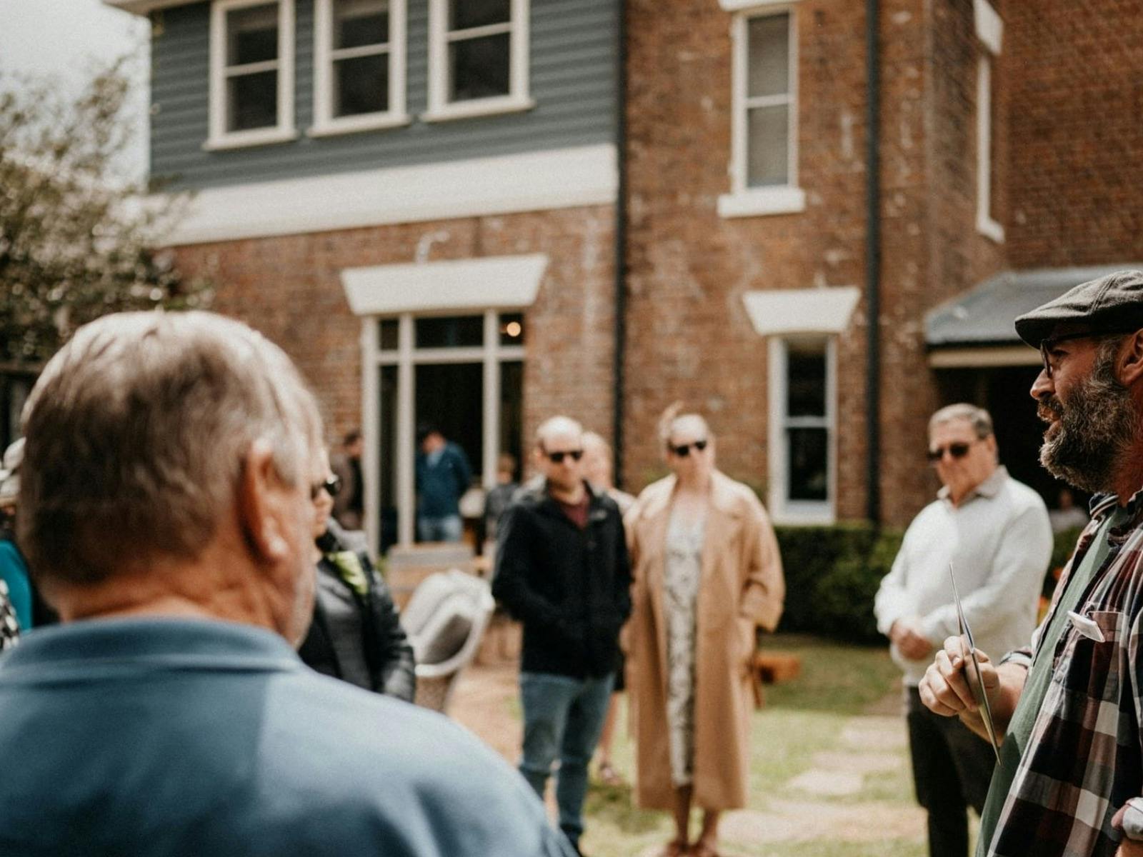 a few people standing and listening in the courtyard of historic estate