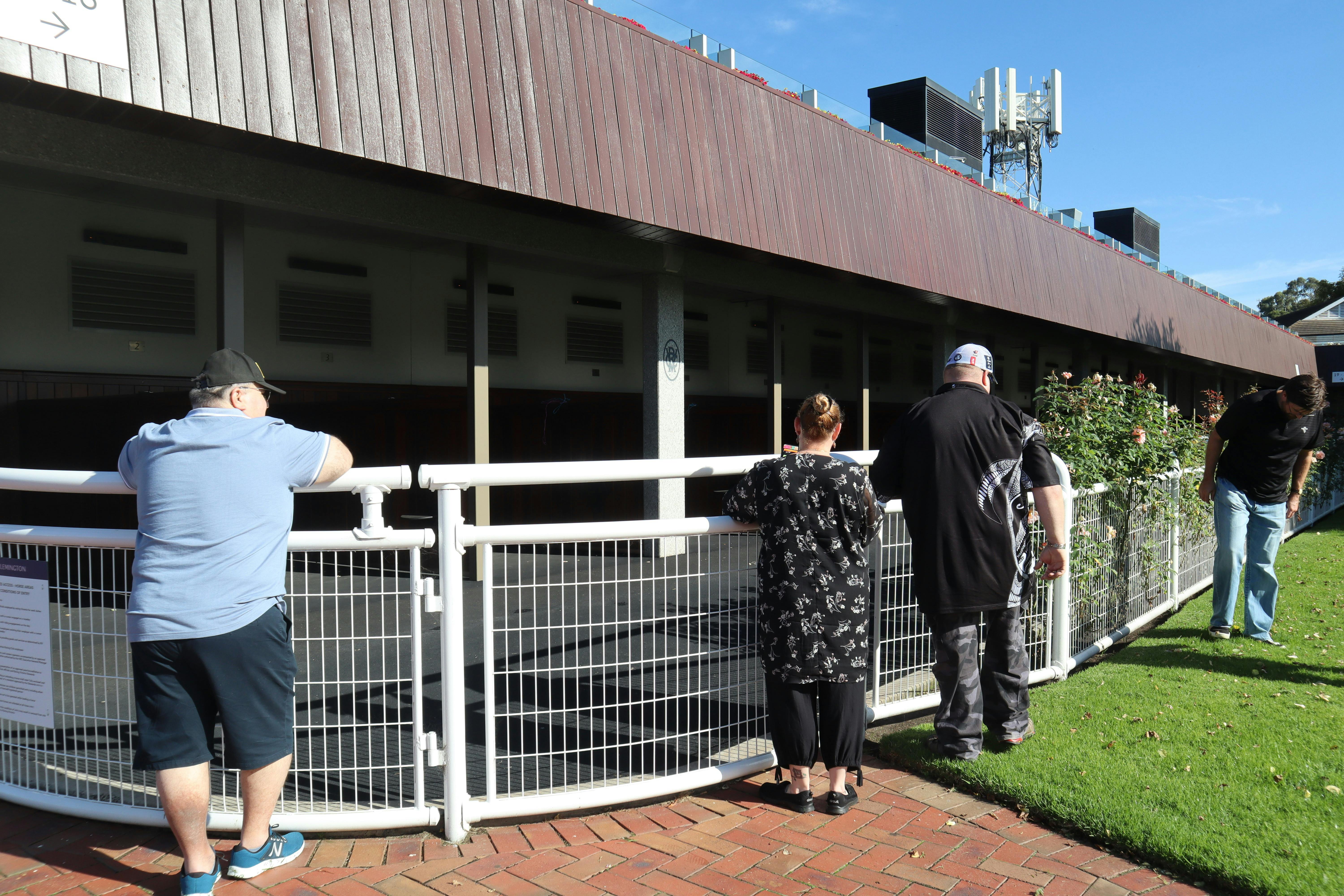 Guests standing at the rail of the Flemington Racecourse race-day stables