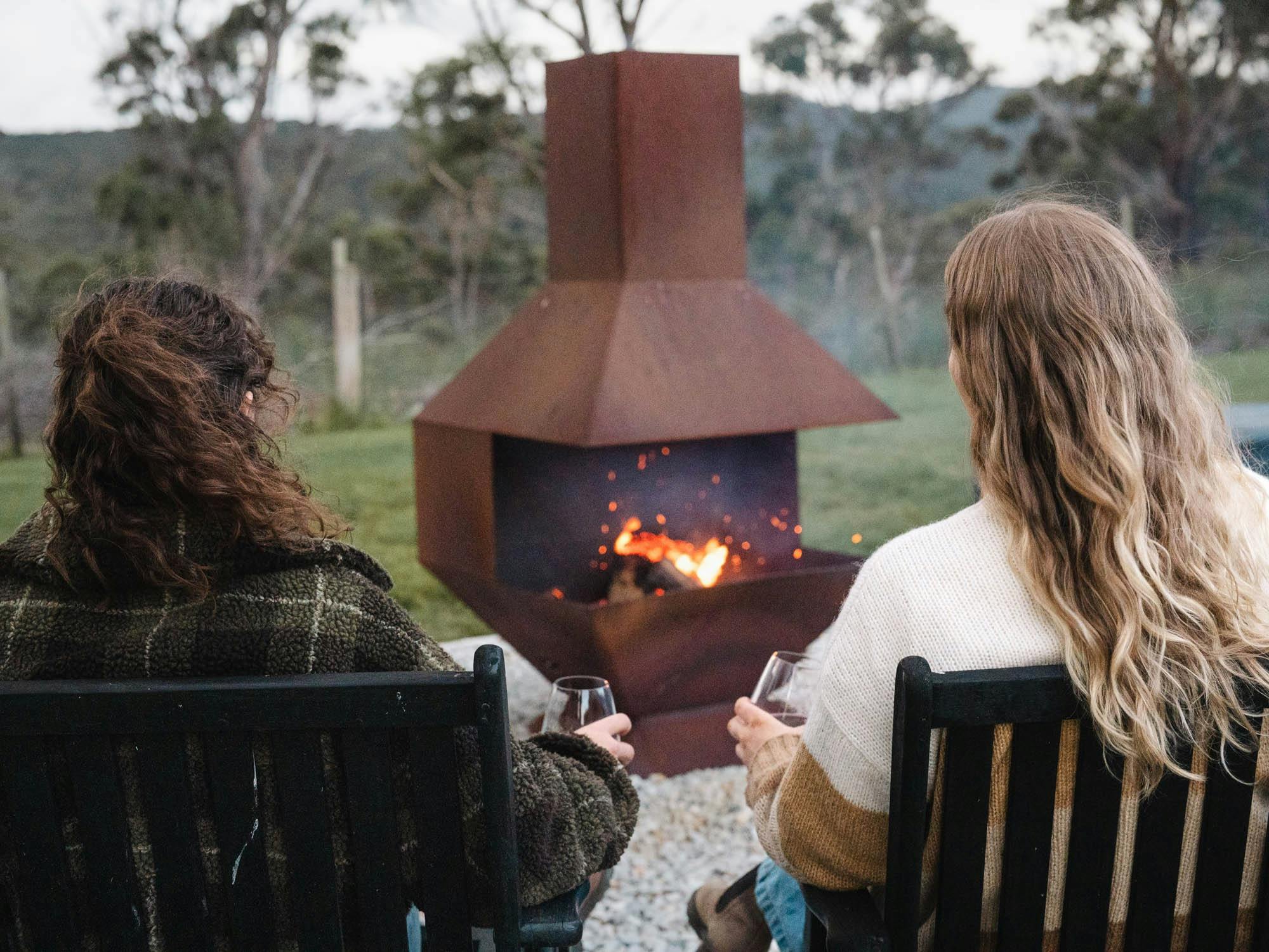 Two guests relaxing in the evening by the warmth of an outdoor fire pit at the lodge.