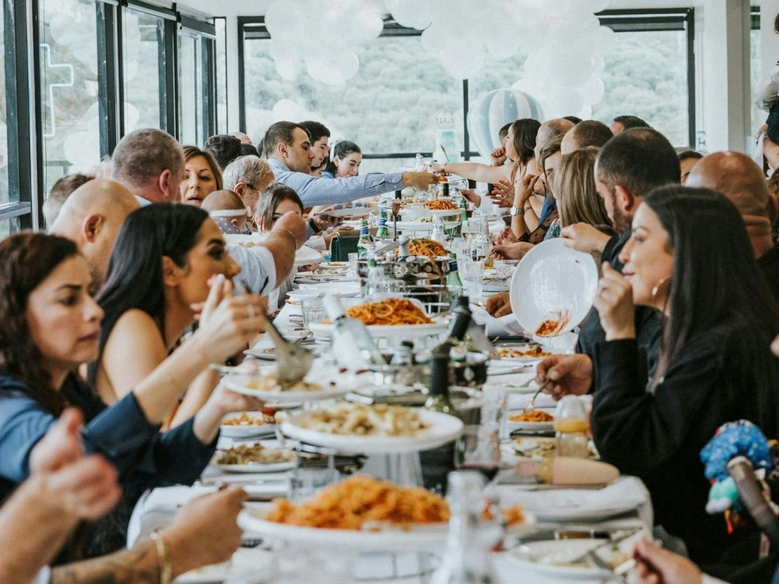 Long table of women enjoying shared Italian Pasts and Pizza