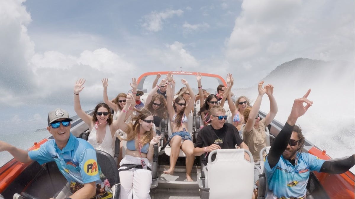 Guests with hands up on jet boat tour.