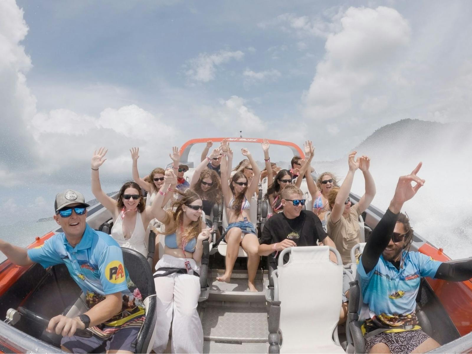 Guests with hands up on jet boat tour.