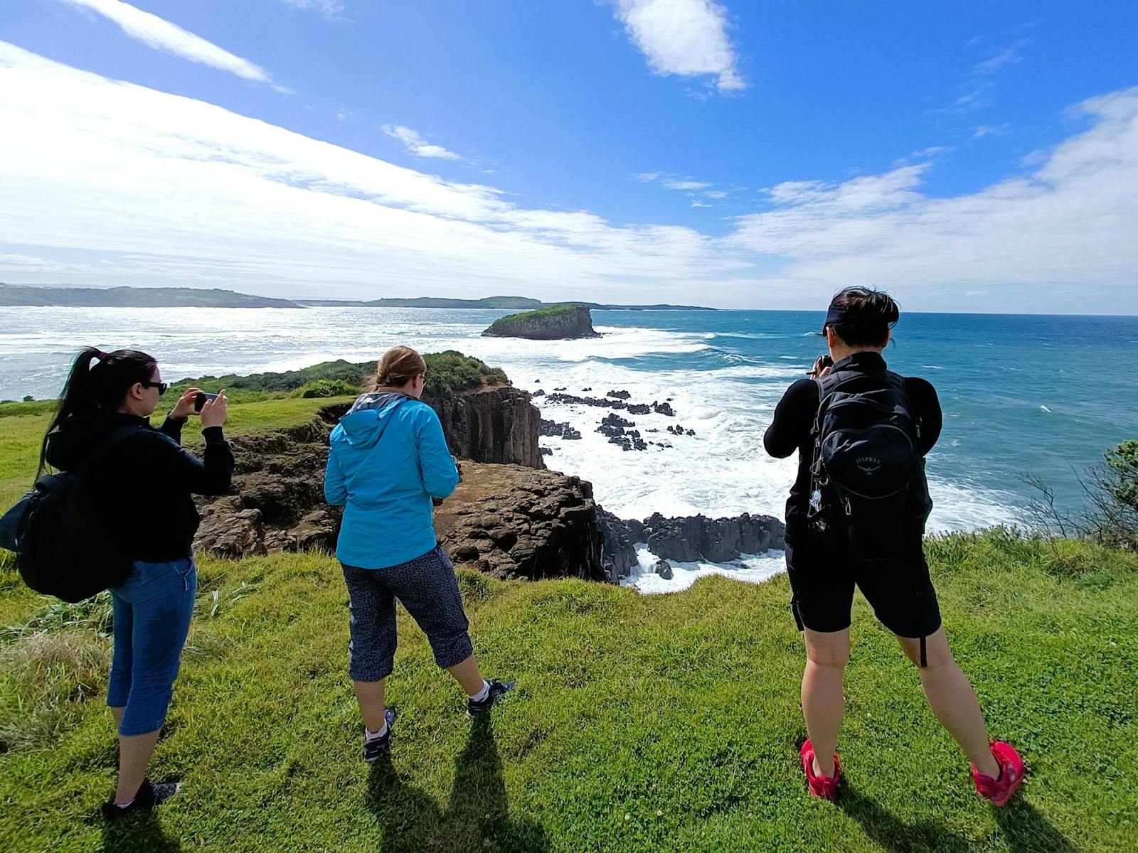 3 people looking over the ocean from a cliff