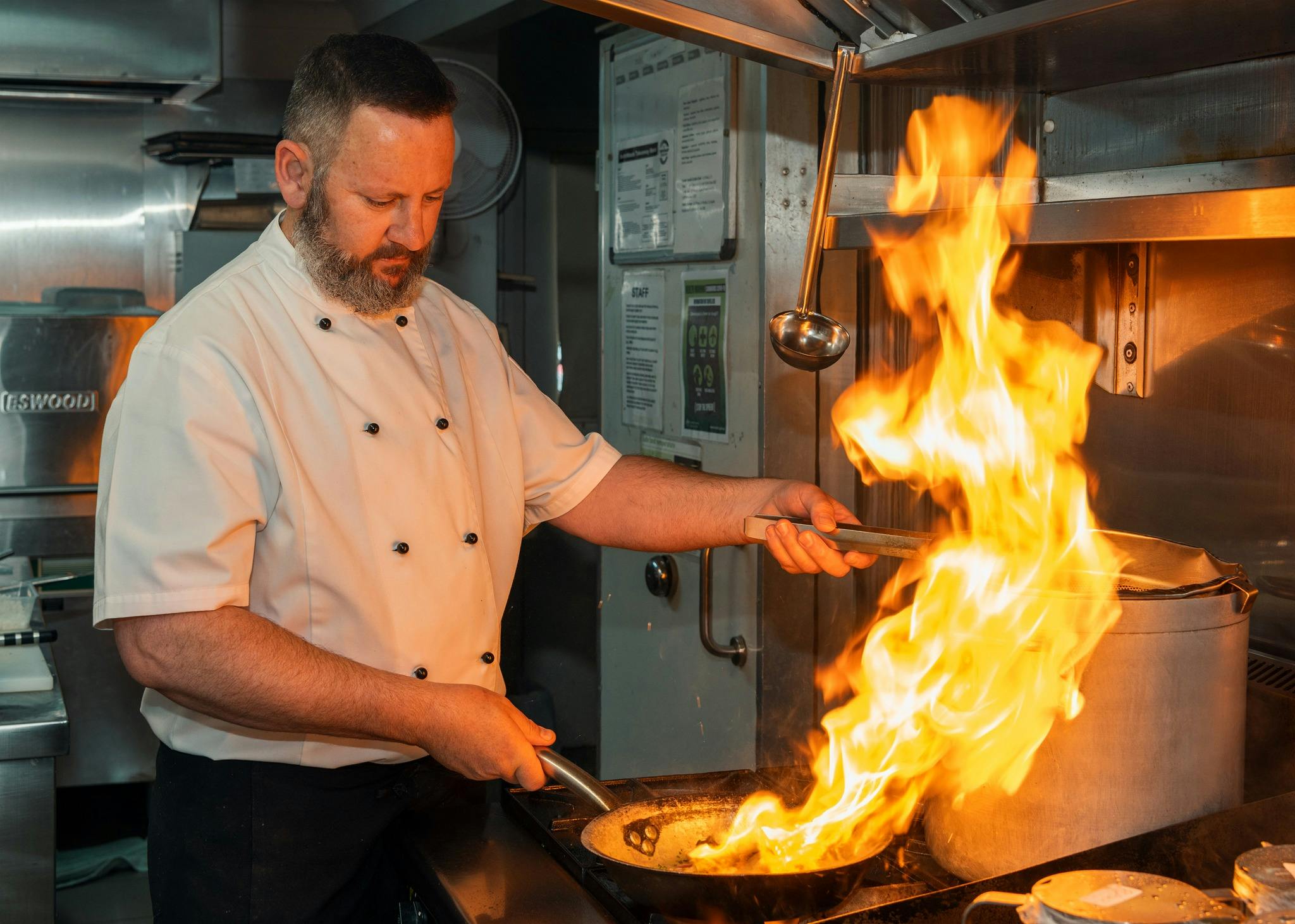Chef Frank prepares a mouth-watering dish with flames on a gas stove top.
