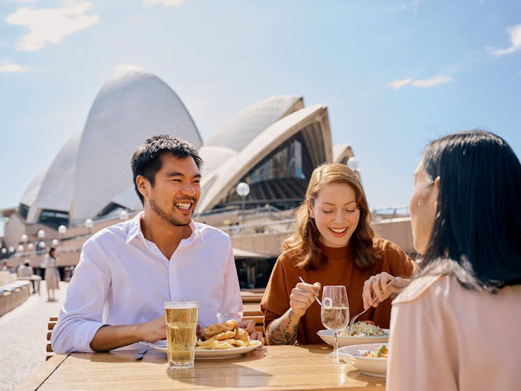 A man and two women dining outside the Opera House