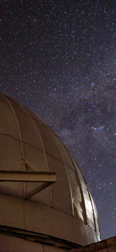 A telescop dome with the Moon and Milky Way Galaxy.