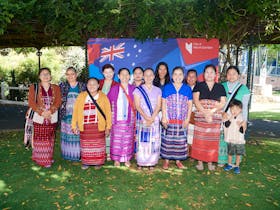 A group of people in traditional cultural clothing stand together smiling