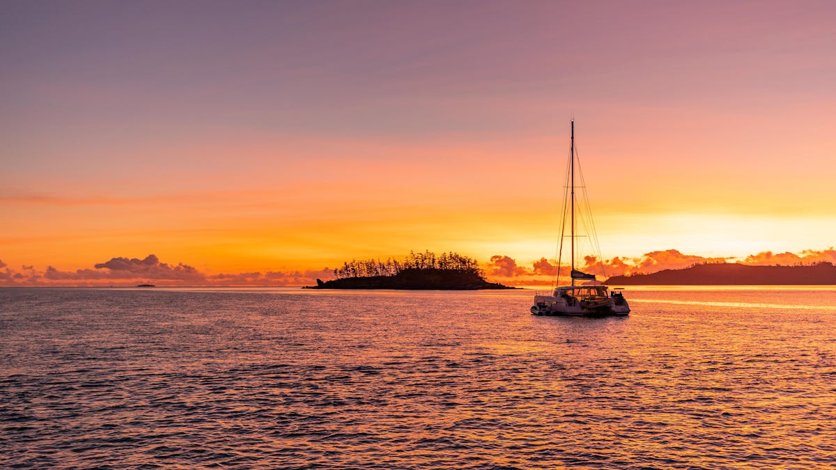 A sailing catamaran moored up whilst the sun sets, in the Whitsundays