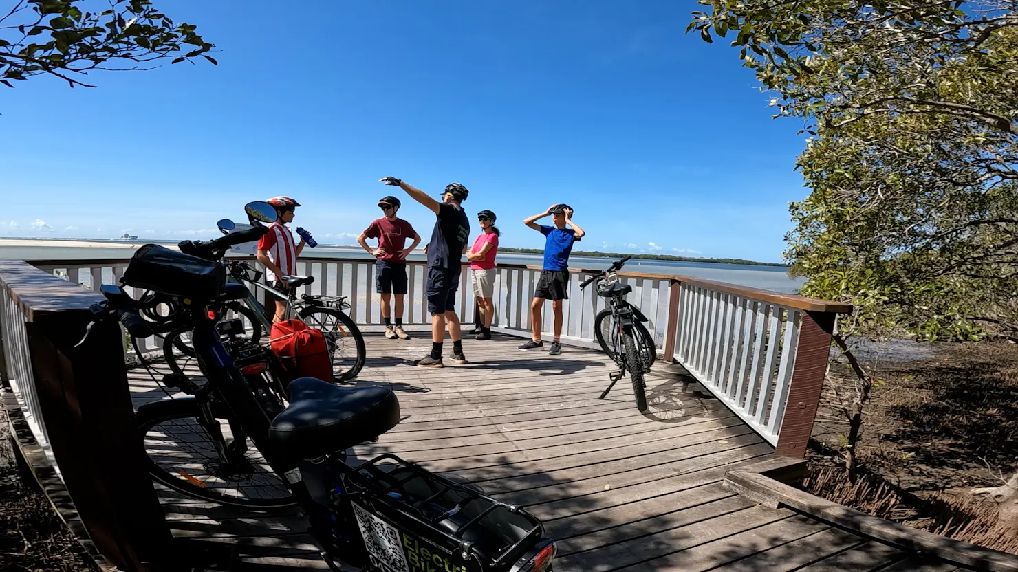 Family of 4 on e-bike tour with marine biologist tour guide, learning about marine environment.