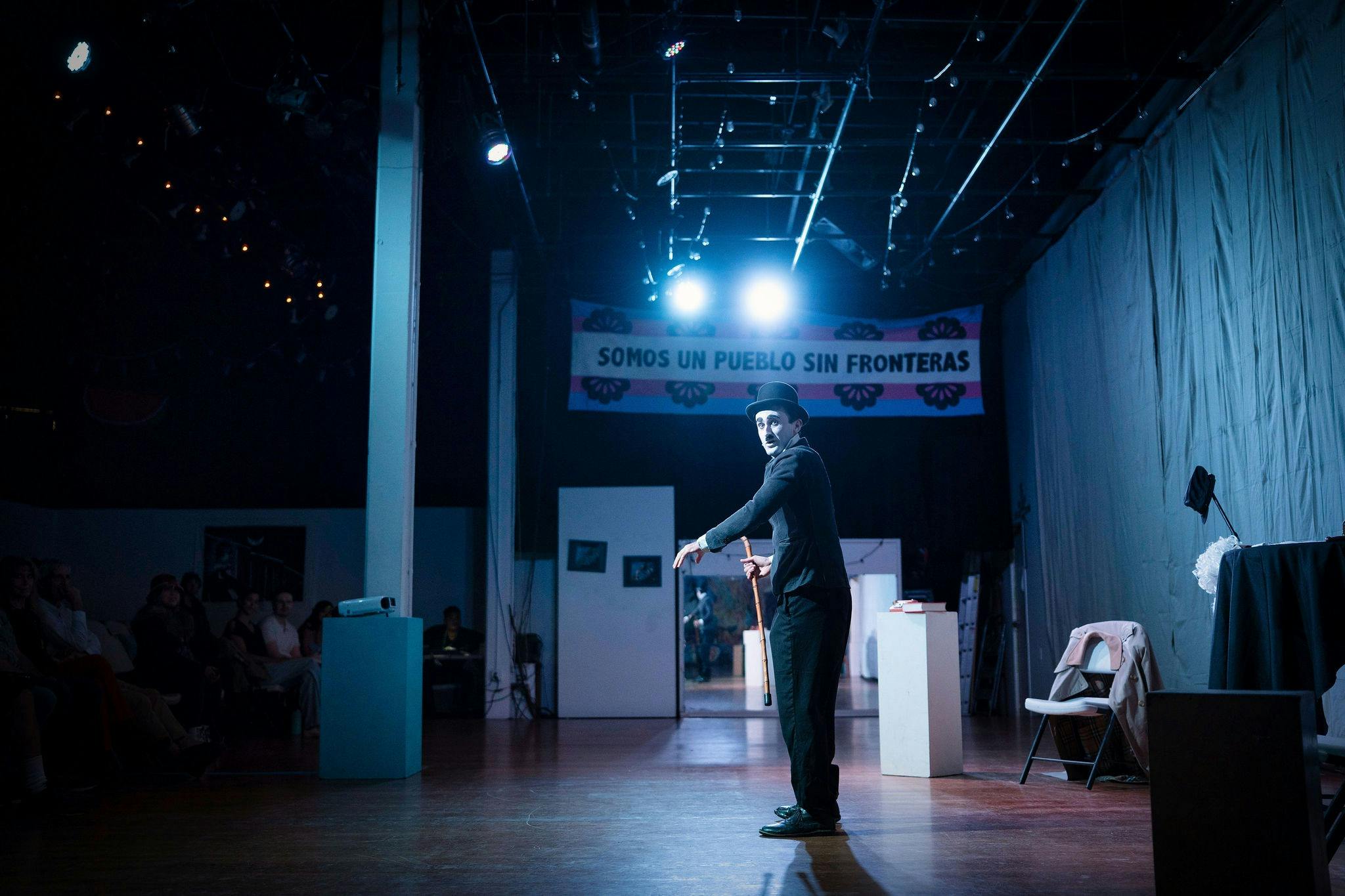 A full body shot of a young man on stage dressed as Charlie Chaplin