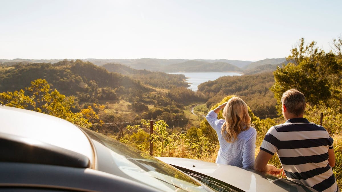 A couple gazing at a sunny horizon overlooking a lake