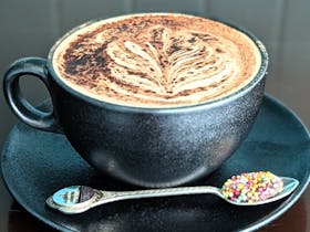 A cup of coffee with a pattern on the milk foam and chocolate sprinkled on top