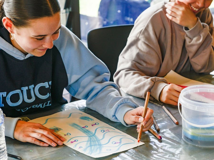 Two students smiling creating gouache paintings