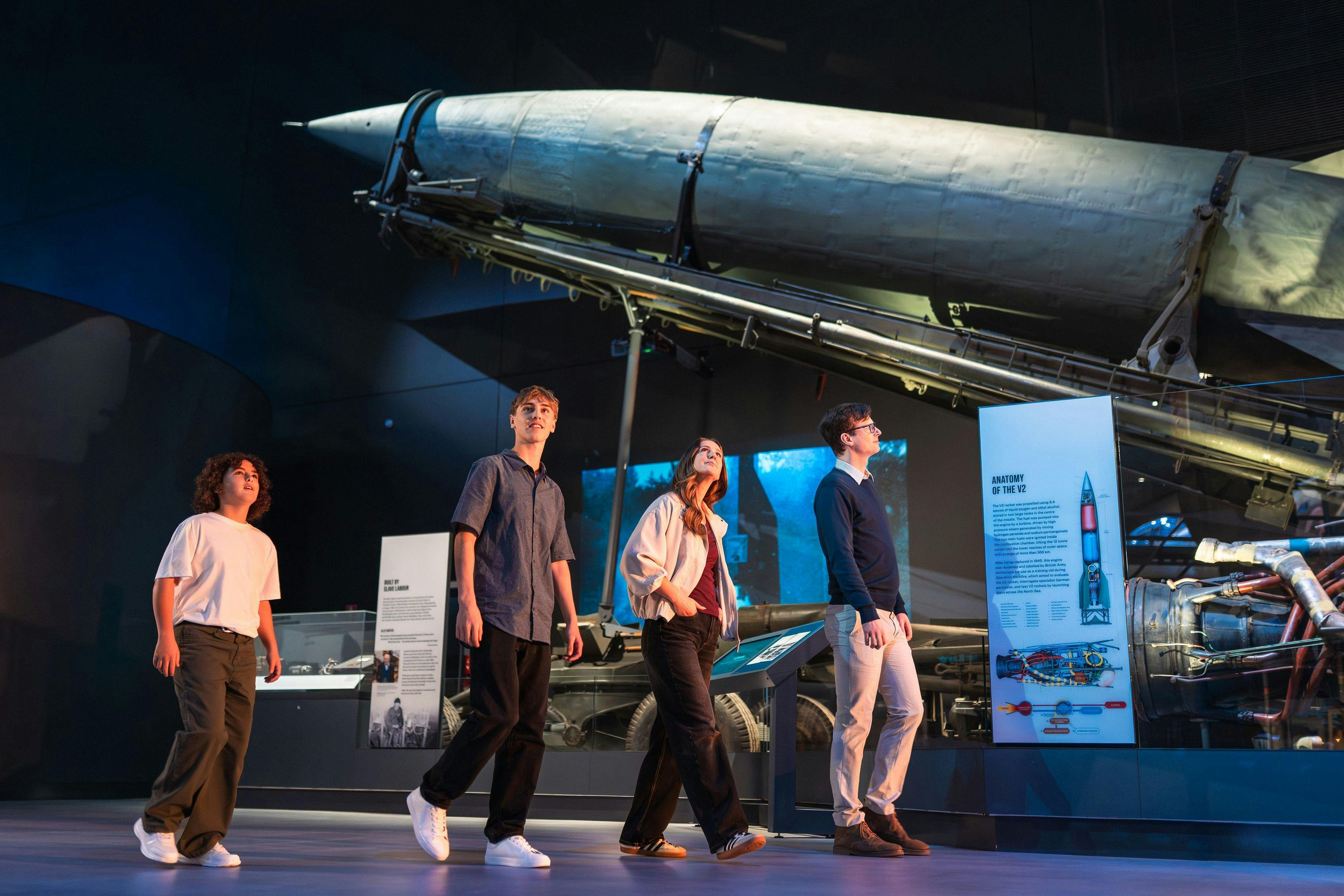 group of visitors walking past a rocket from the second world war