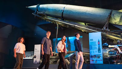 group of visitors walking past a rocket from the second world war