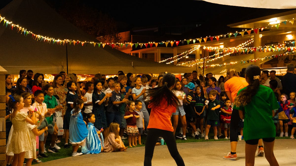 Children and families dancing together at the Prologue Party under colourful lights and bunting. Nat