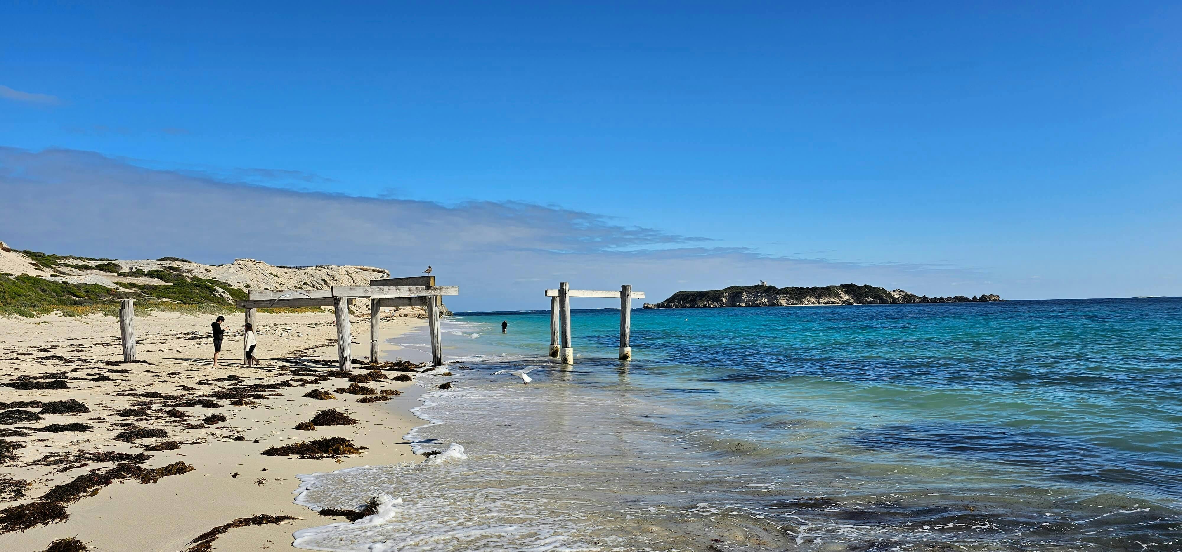 Remains of old jetty in tranquil blue water with island in background