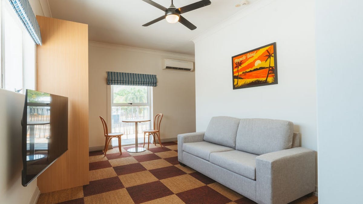 Guest room with sofa, TV and balcony seating area offering comfortable stays at Hotel Allen.