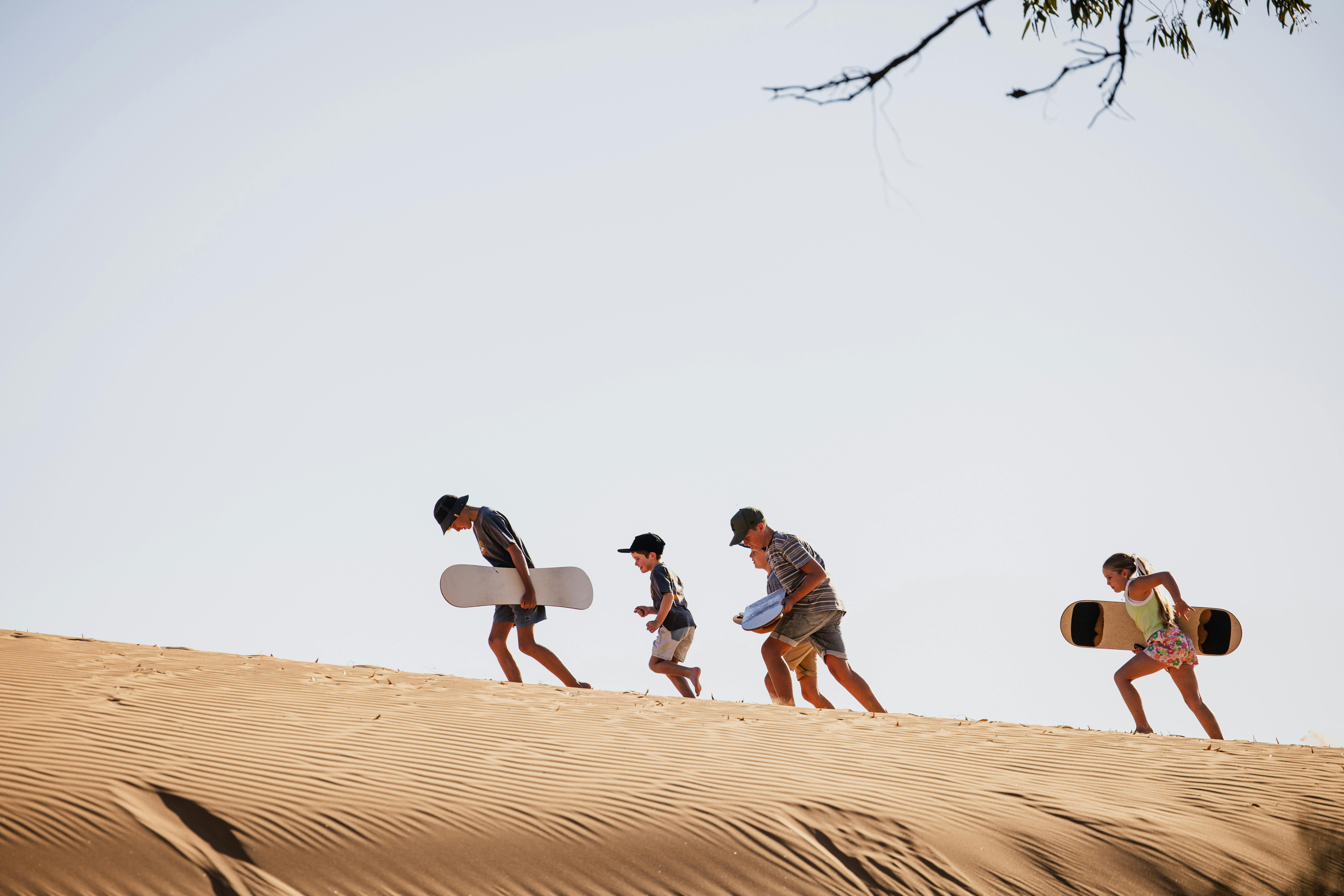 Children getting ready to sandboard on dunes