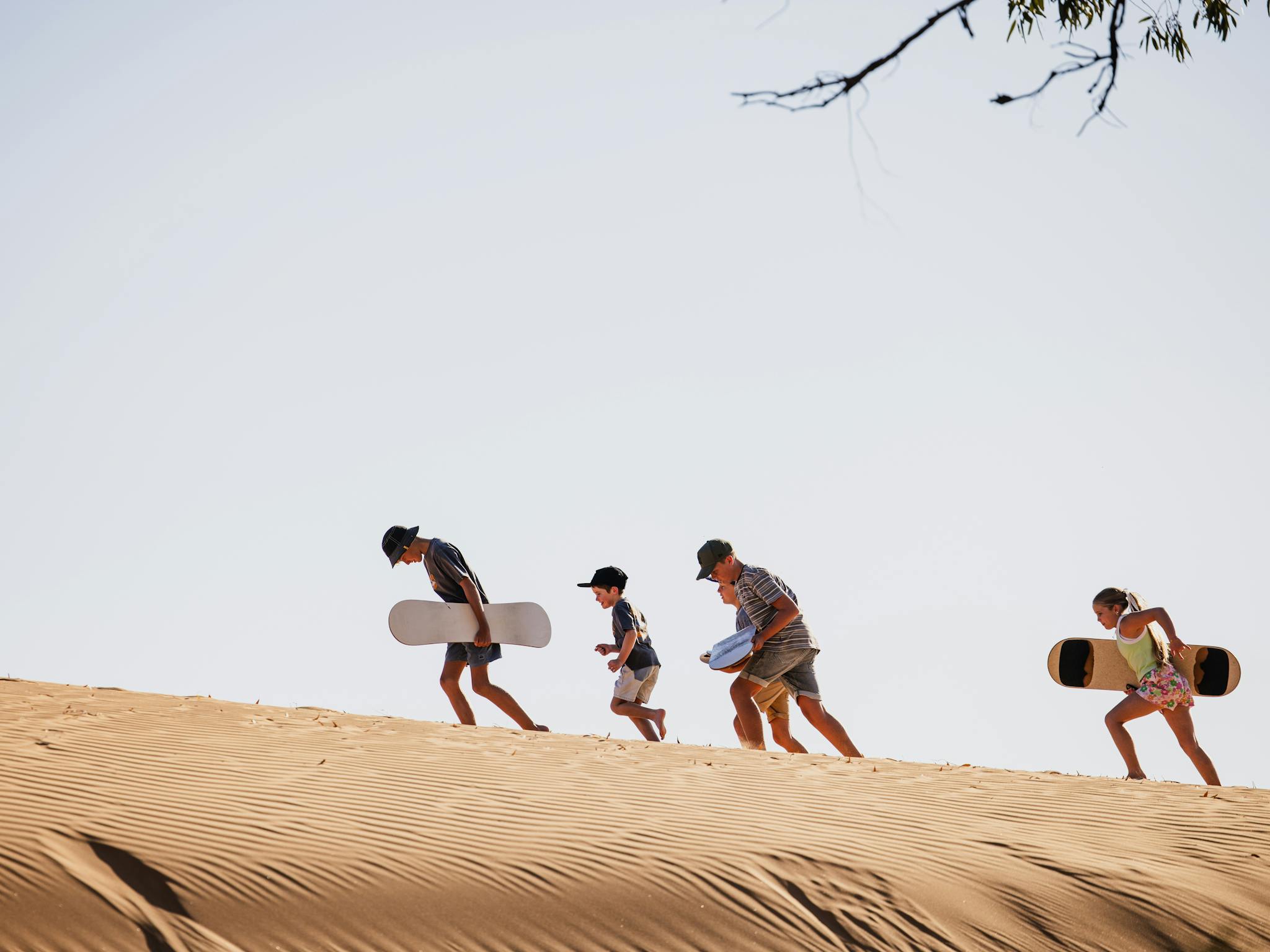 Children getting ready to sandboard on dunes