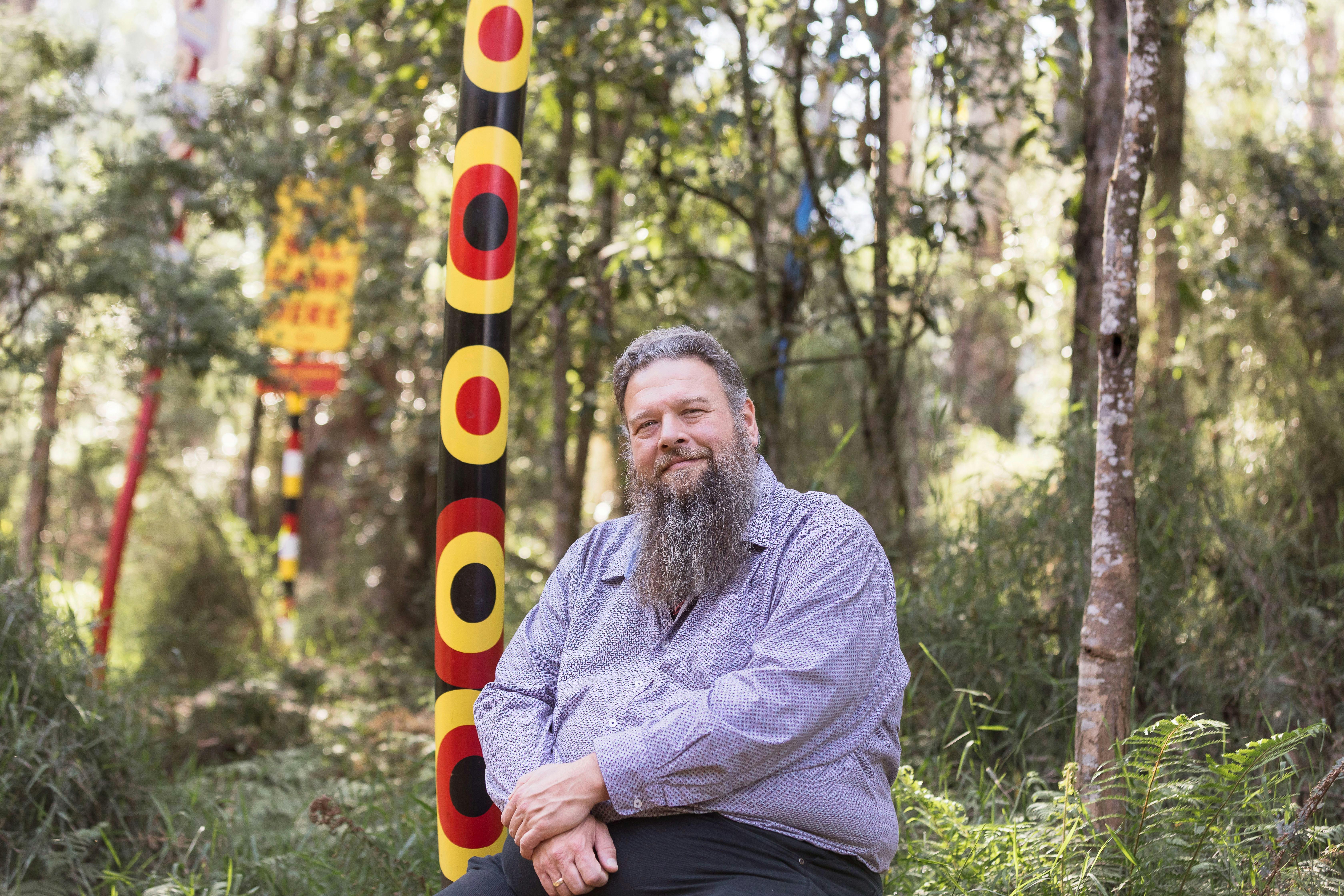 An artist with his sculpture in the forest