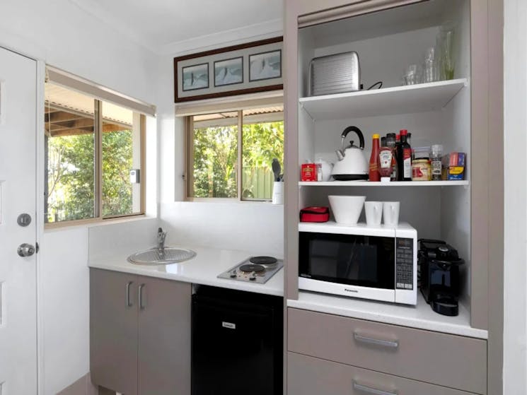 Well-equipped kitchen with electric cooktop, microwave, and fridge
