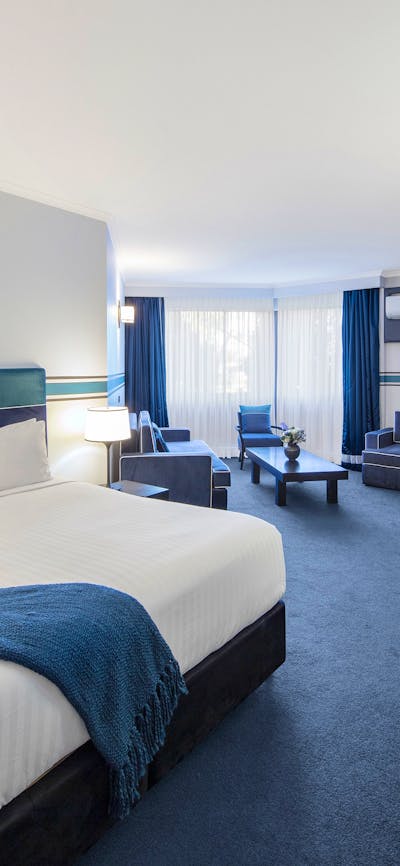 Deluxe King Room bed, working desk and lounge area