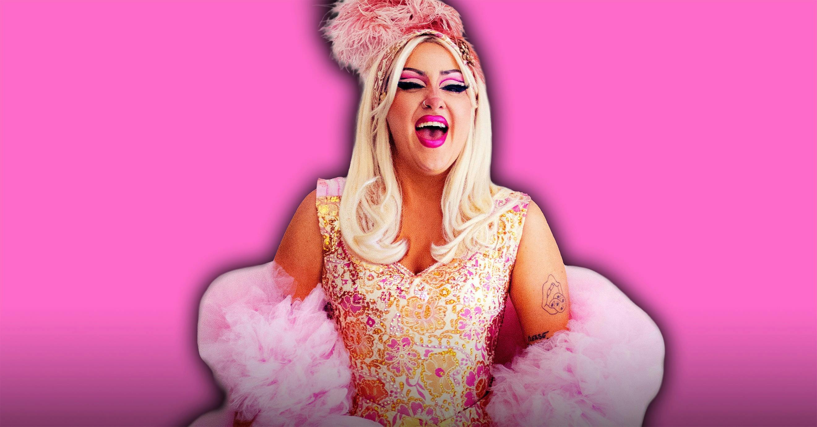 A woman in a corset dress and a tulle boa, laughing with feathers in her hair