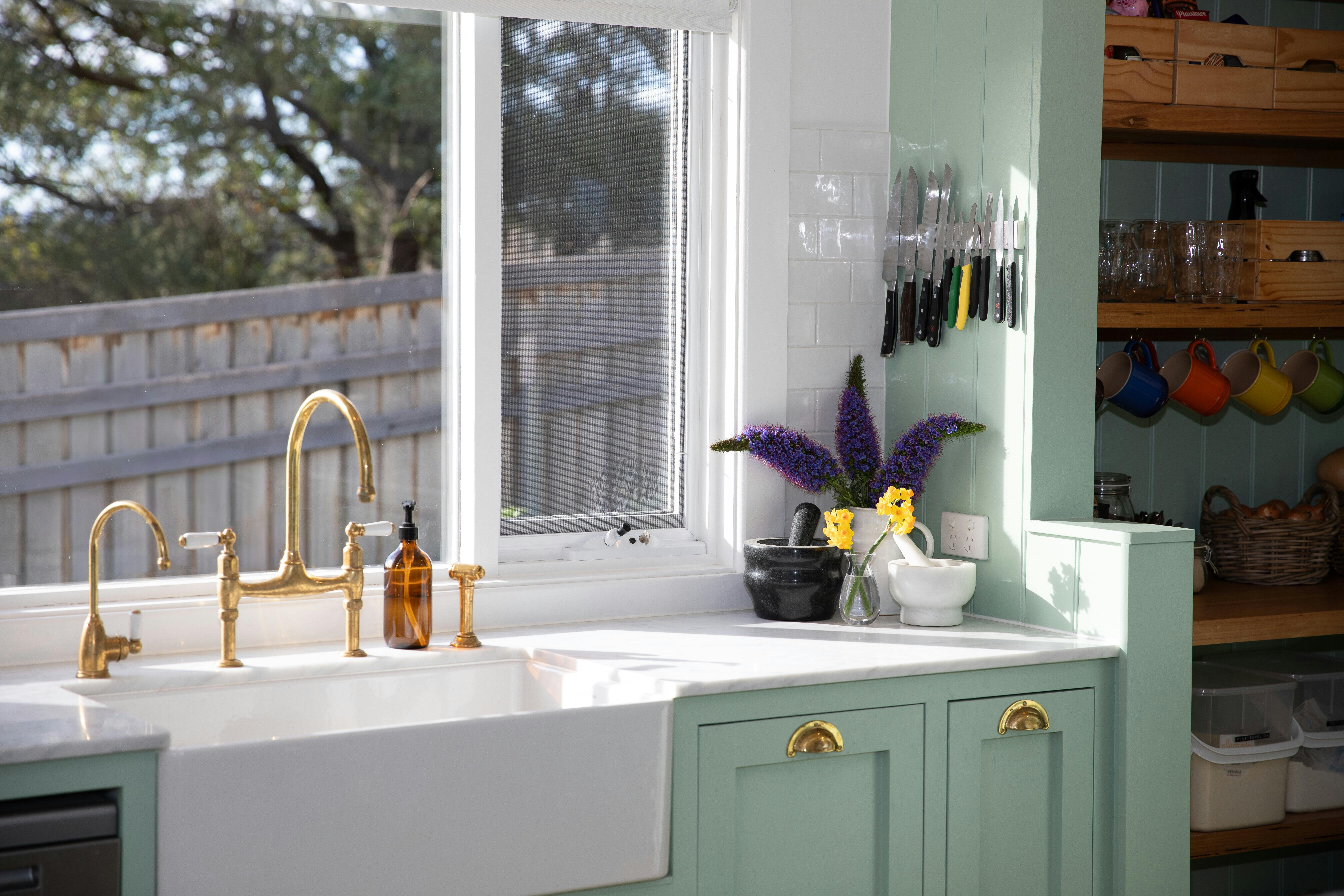 Farmhouse sink with brass tap and fresh flowers at Florian Cottage kitchen, Tasmania.