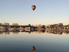 Balloon over the peir with the shimmering reflection below.