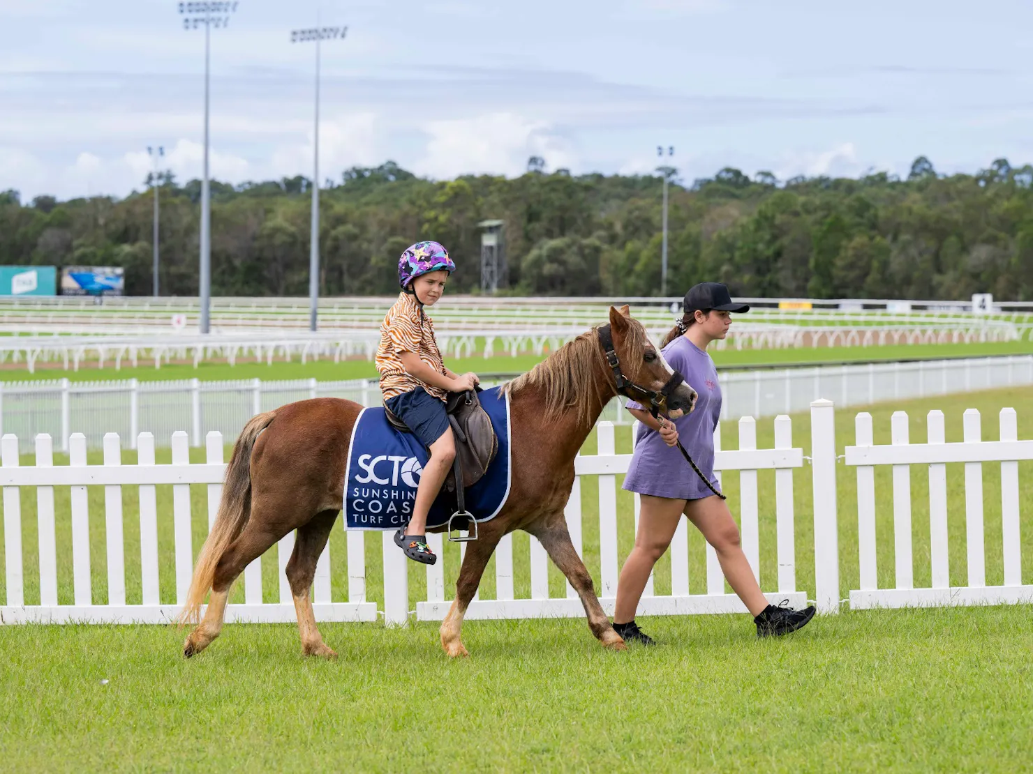 Little boy riding a pony on the lawn