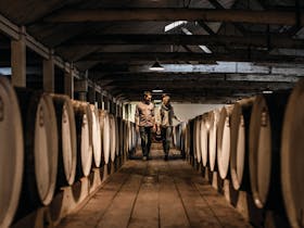 Walking through a dimly lit cellar among wine barrels