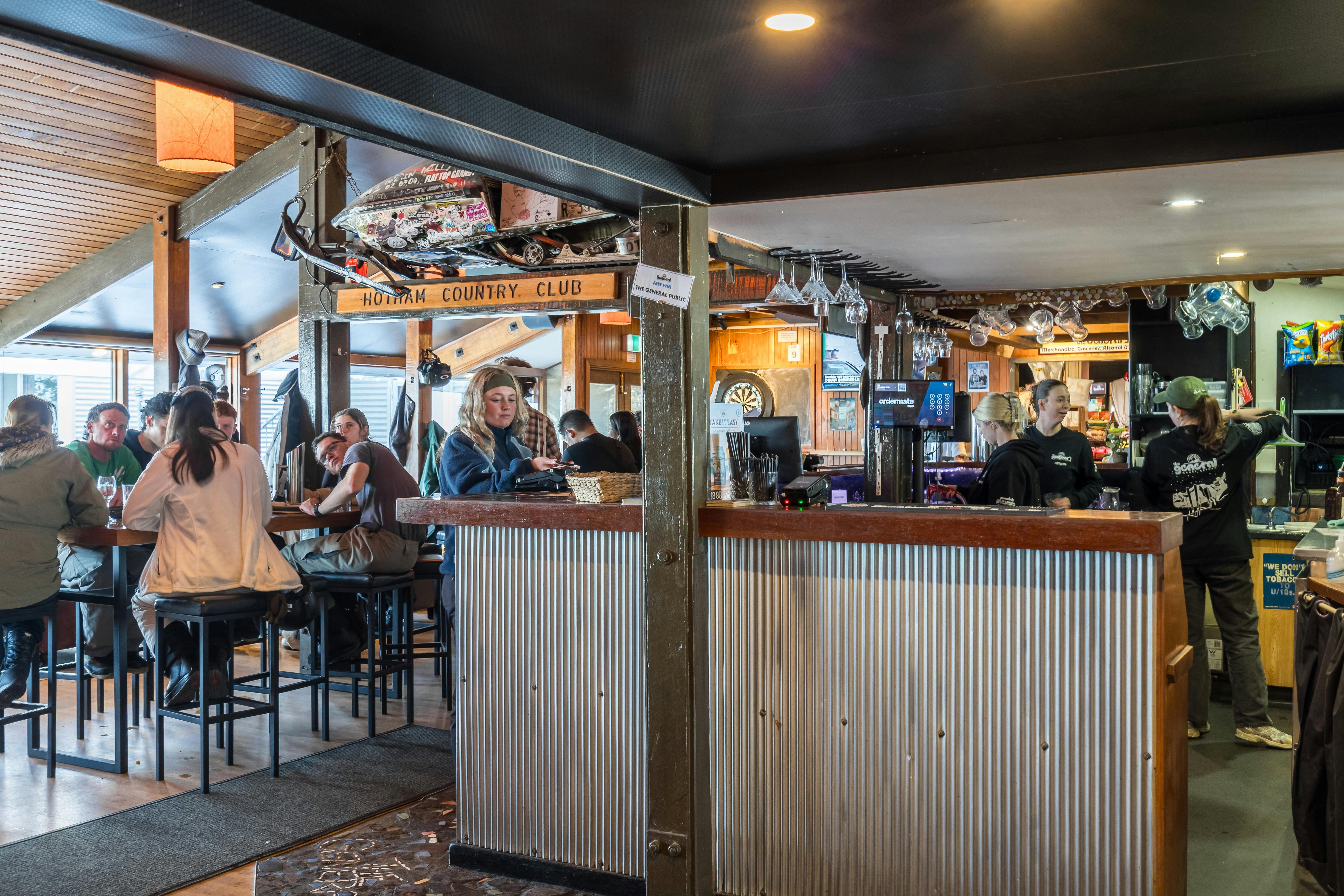Downstairs bar with high tables and iconic skidoo mounted above the bar.