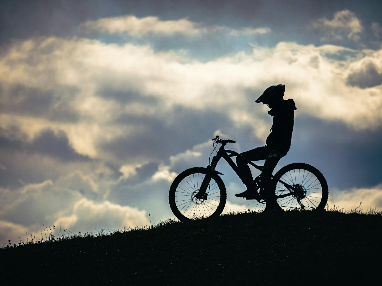 silhouette of person sitting on mountain bike on a hill