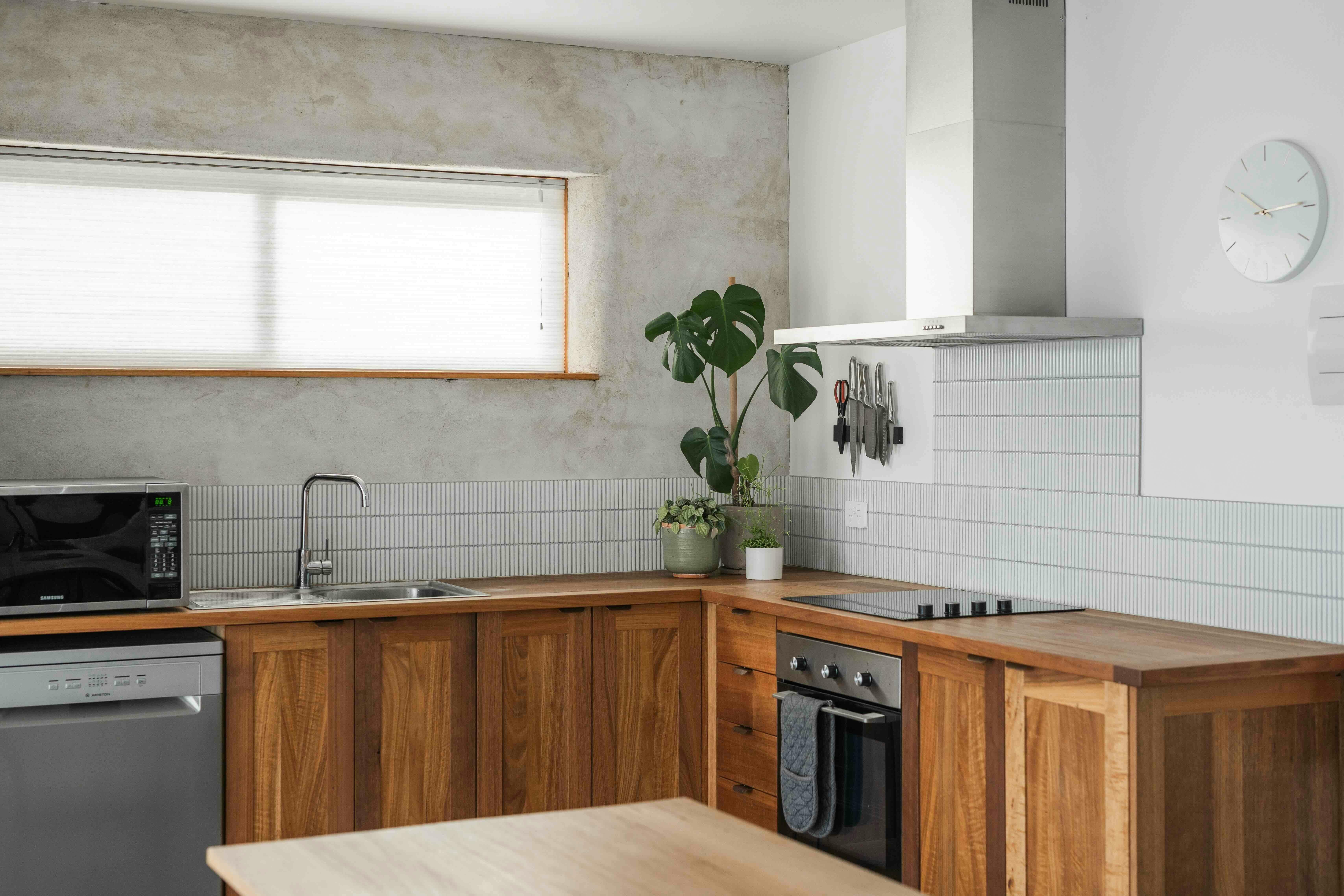 A kitchen with a microwave, sink, oven, stove top and rangehood.