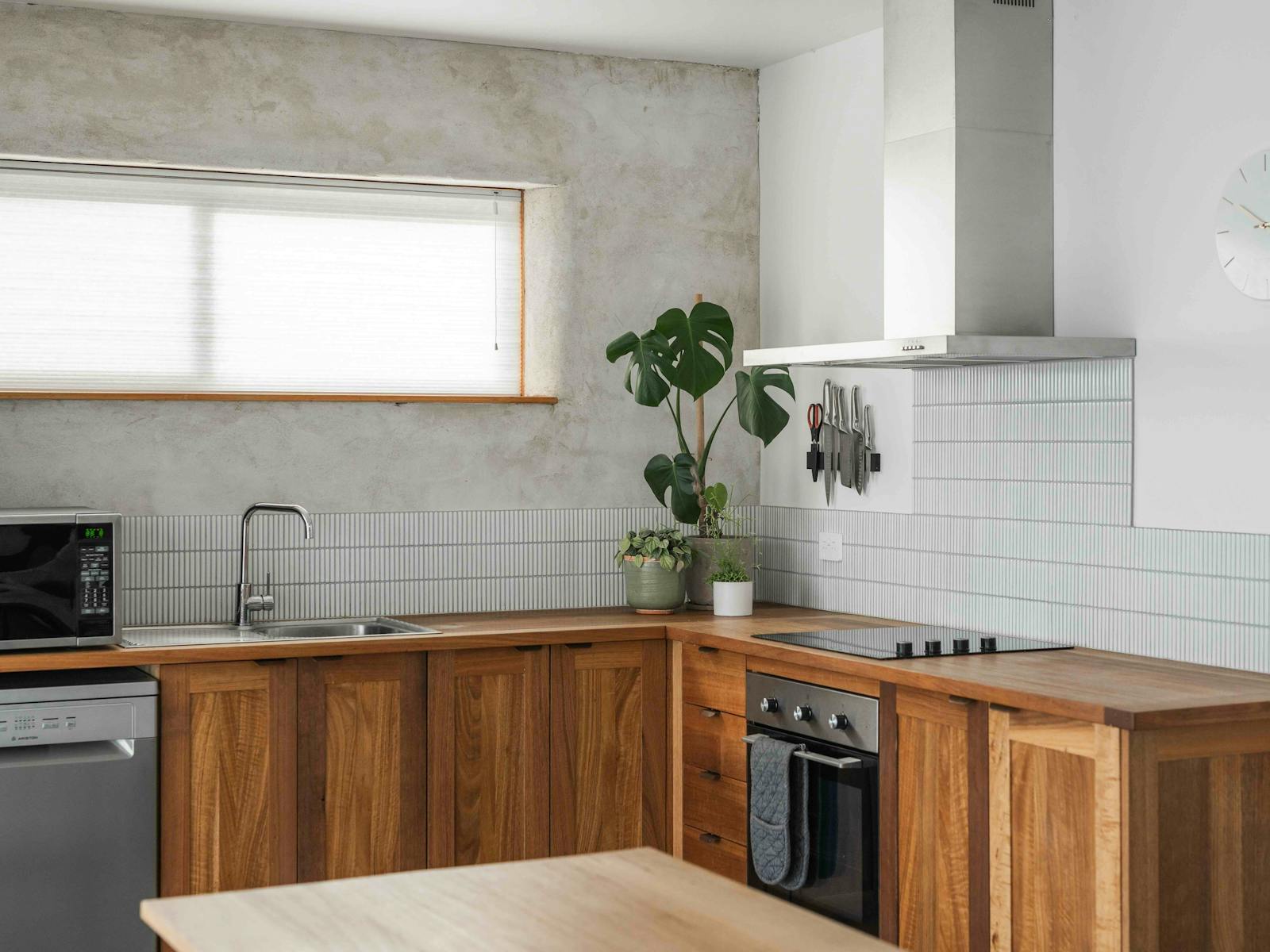 A kitchen with a microwave, sink, oven, stove top and rangehood.