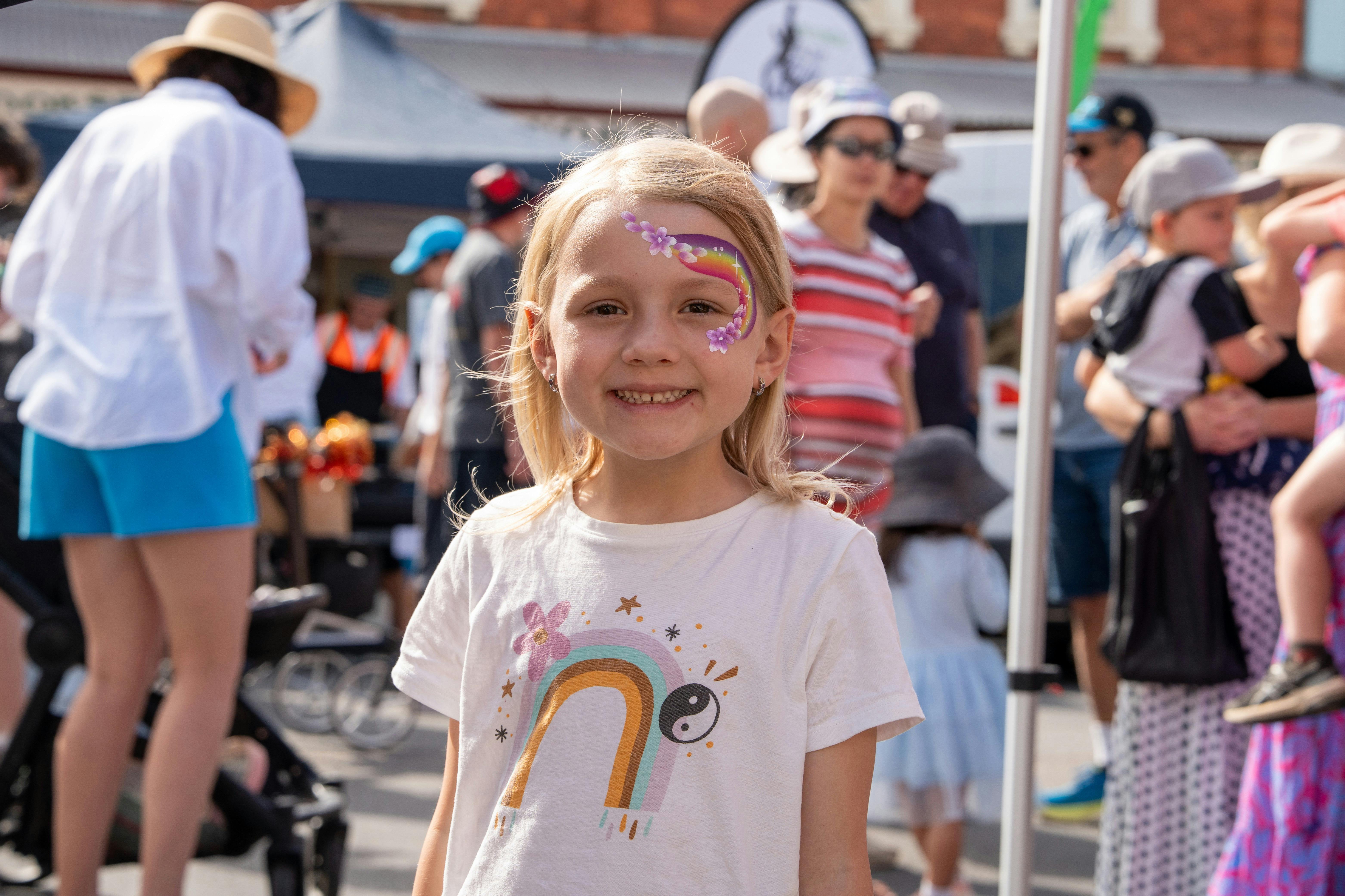 Young girl with face painted in front of large crowd