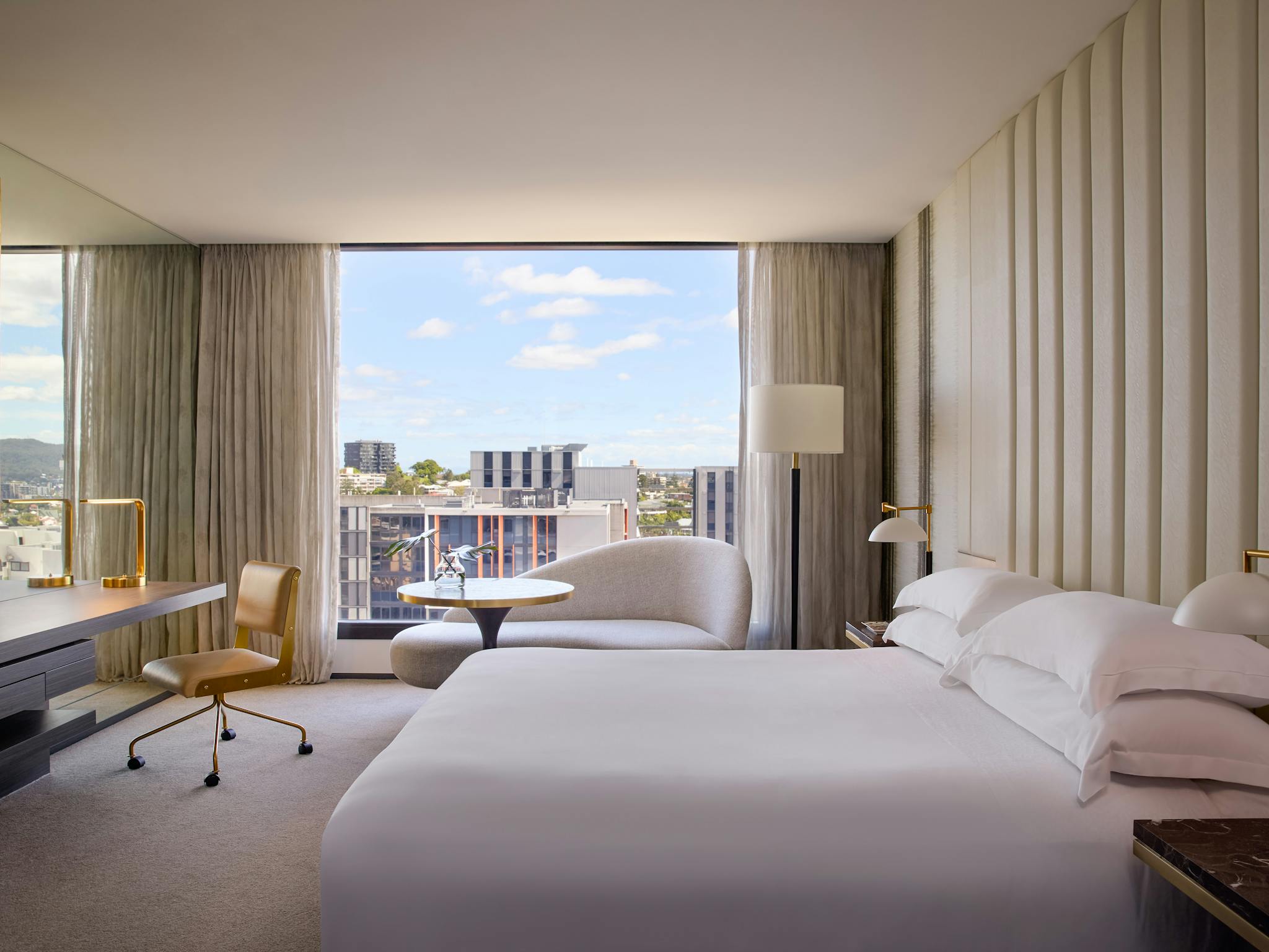 Luxury hotel suite with gold-framed mirror and floor-to-ceiling windows overlooking Brisbane Luxury hotel suite with gold-framed mirror and floor-to-ceiling windows overlooking Brisbane