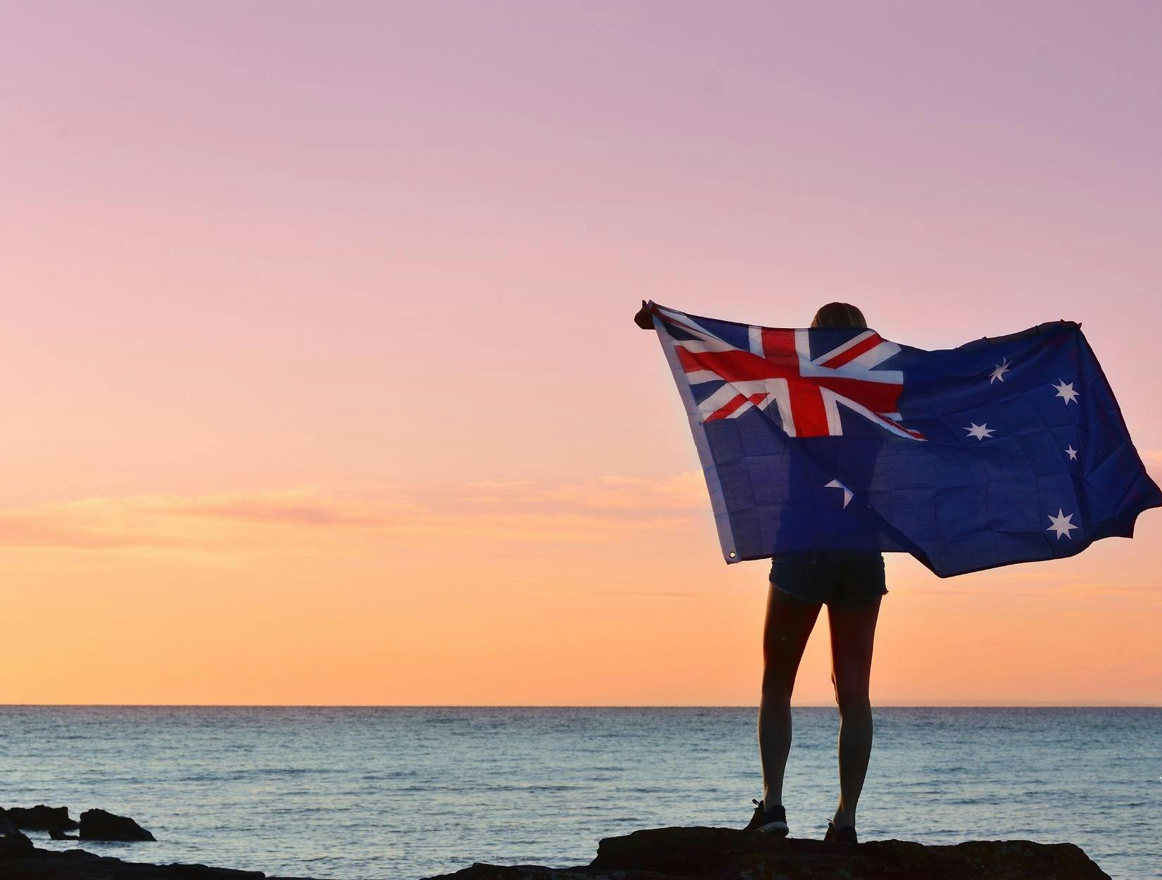 Australian flag held up before the ocean