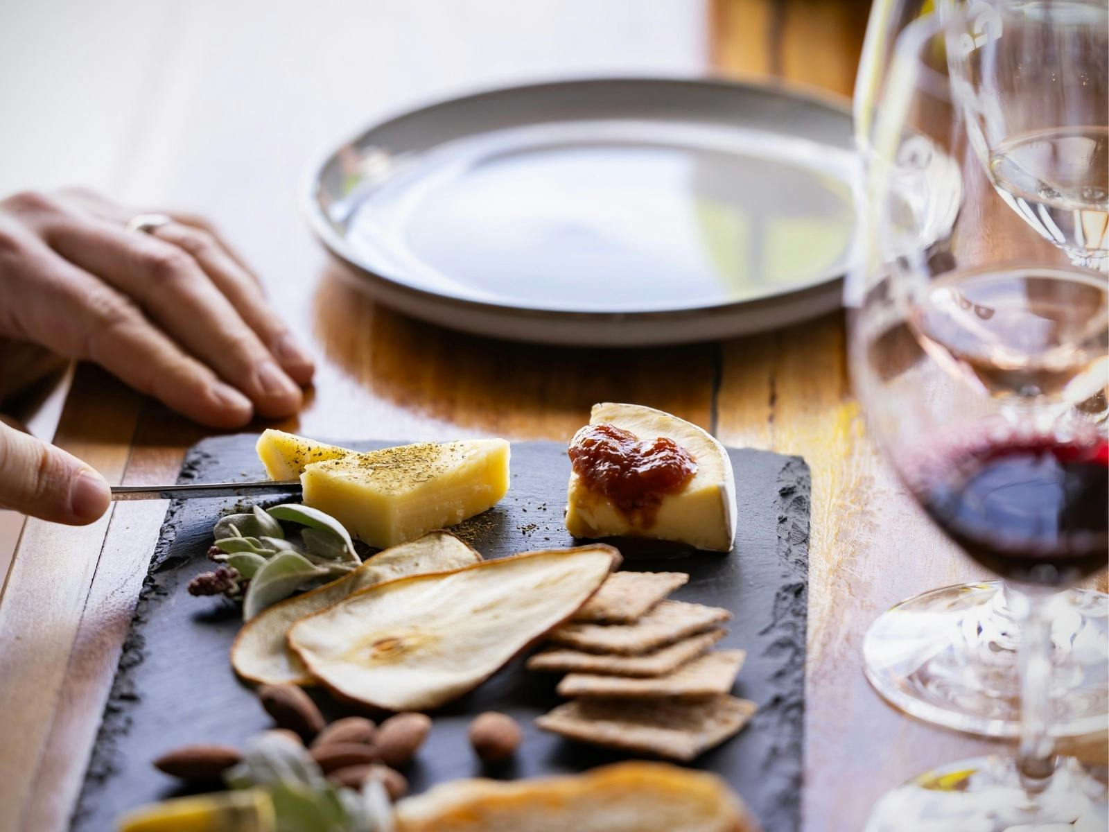 Hand cutting into cheese on a Native Tasting plate