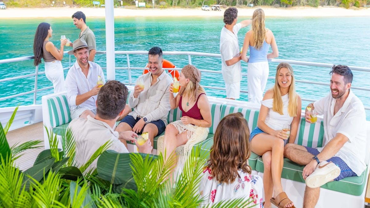 Guests relaxing with a cocktail onboard the See Moreton vessel, enjoying the sea view