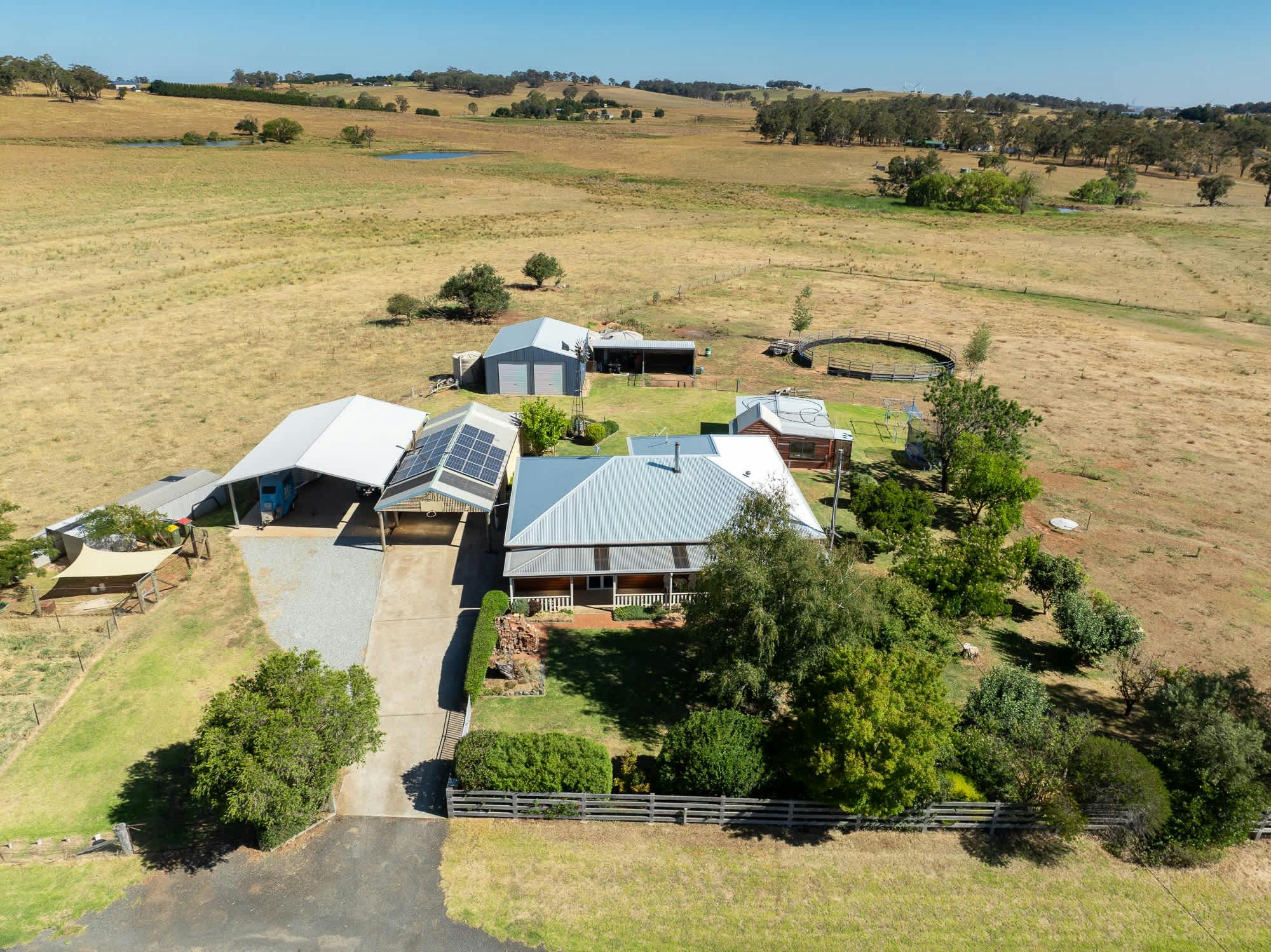 Large rural area with the homestead, carport, sheds and fenced backyard.