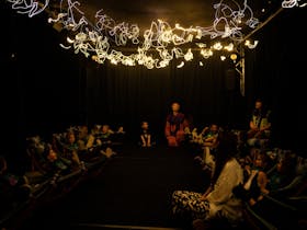 A dark room with children looking up at the ceiling which is full of moving lights