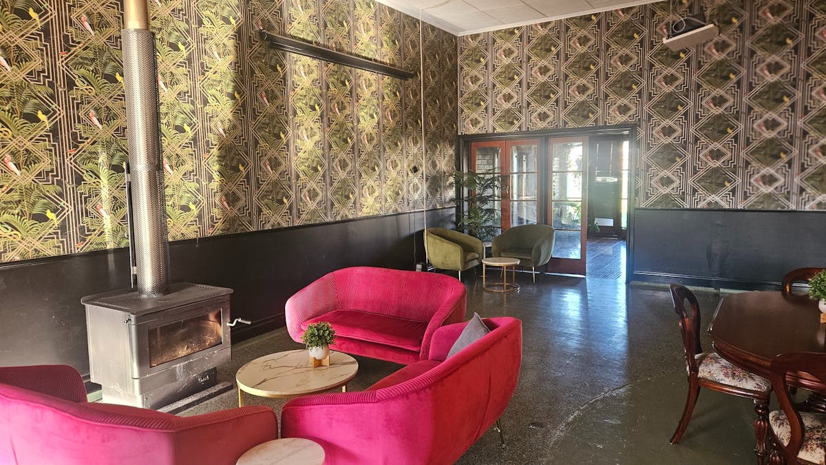 Red sofas around a wood fire in the art deco inspired bar on The Retreat Cunnamulla in the Old RSL