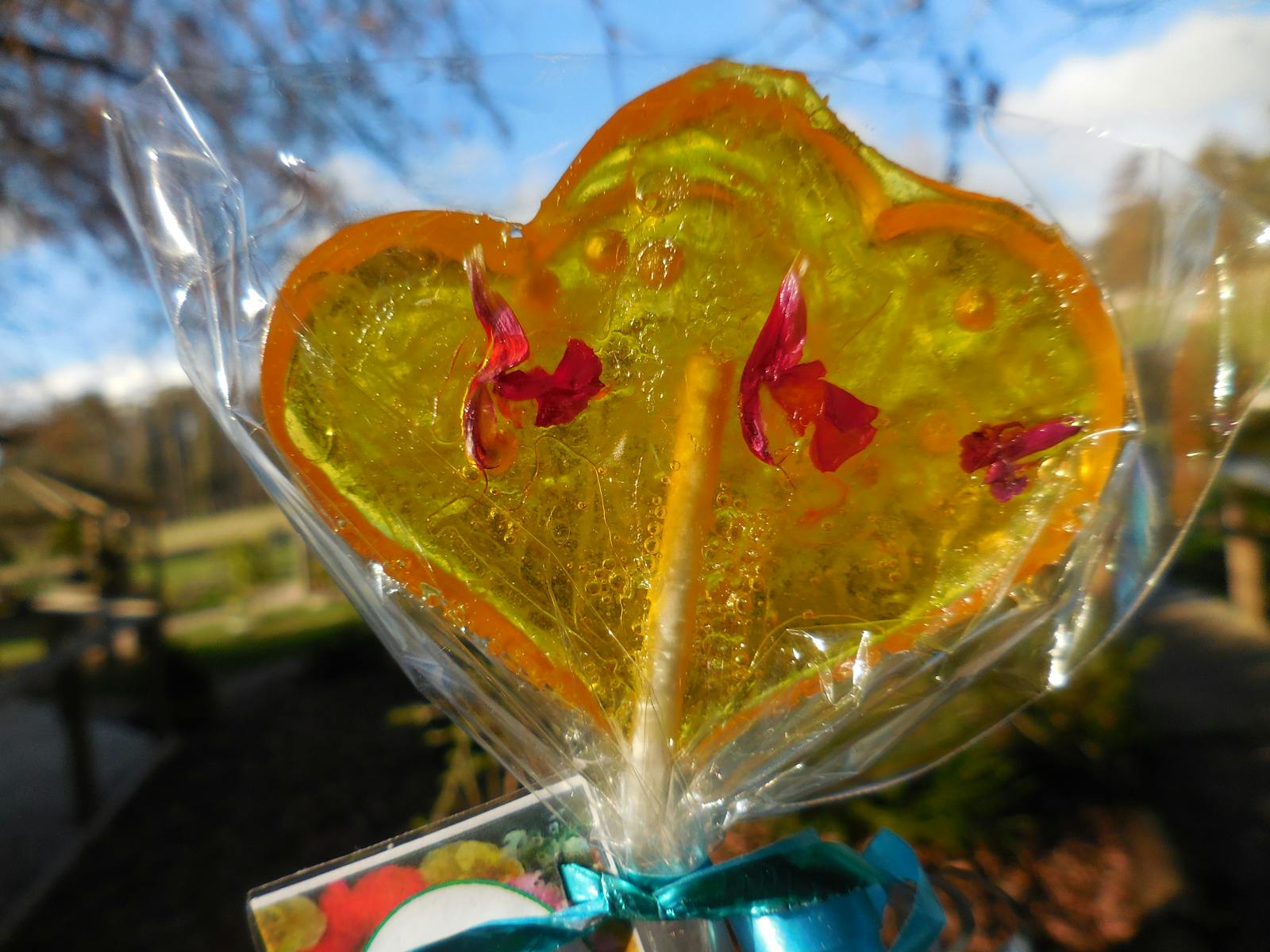 Lemon lollipop in the shape of a double heart, inset with pink edible flowers