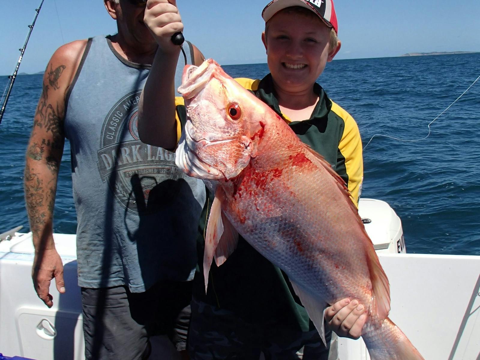 Young boy holding a fish that he has caught whilst on tour, another angler standing behind him. Young boy holding a fish that he has caught whilst on tour, another angler standing behind him.