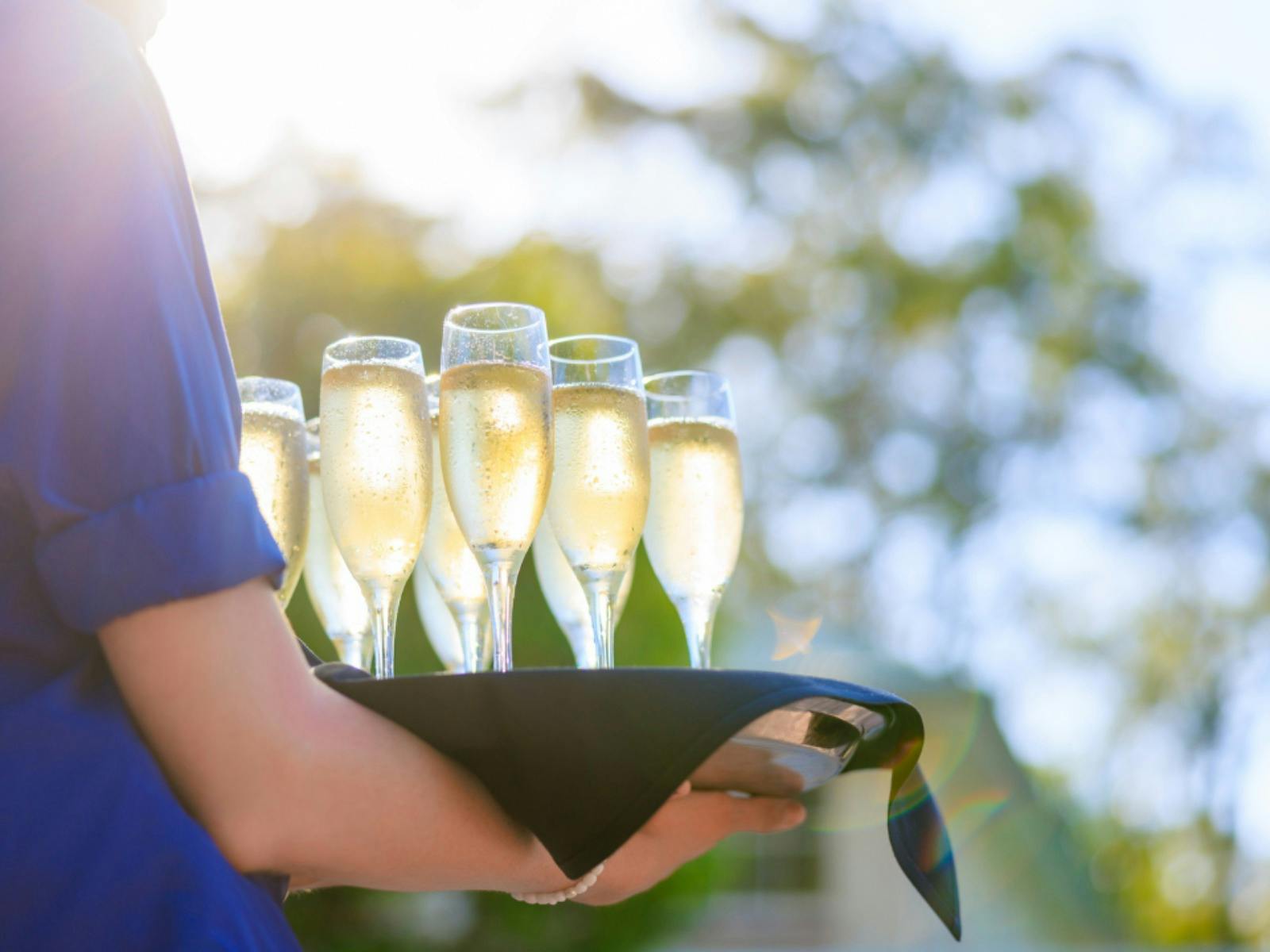 A try of glasses being carried by a waiter filled with Champagne
