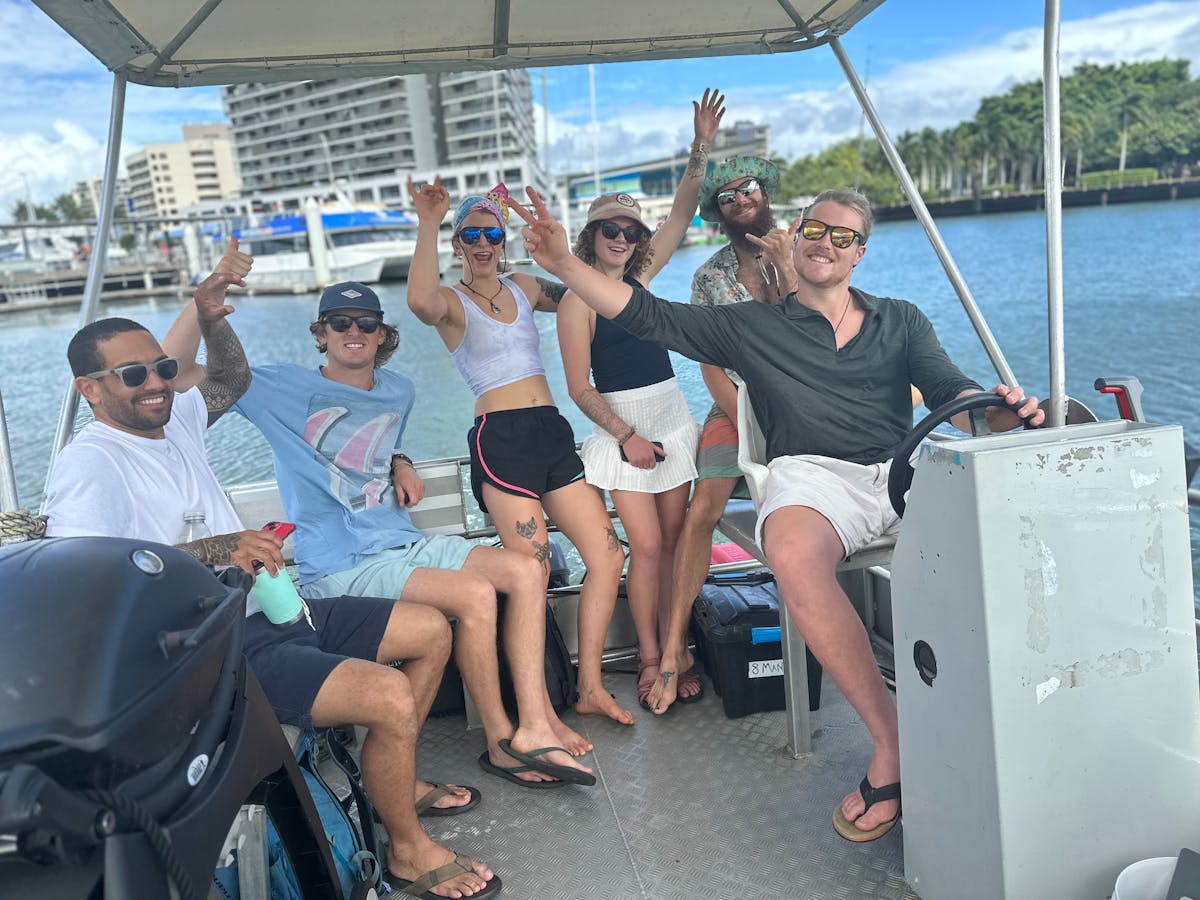 Smiling group of 6 friends waving on a Cairns Boat Hire Pontoon in Tropical North Queensland