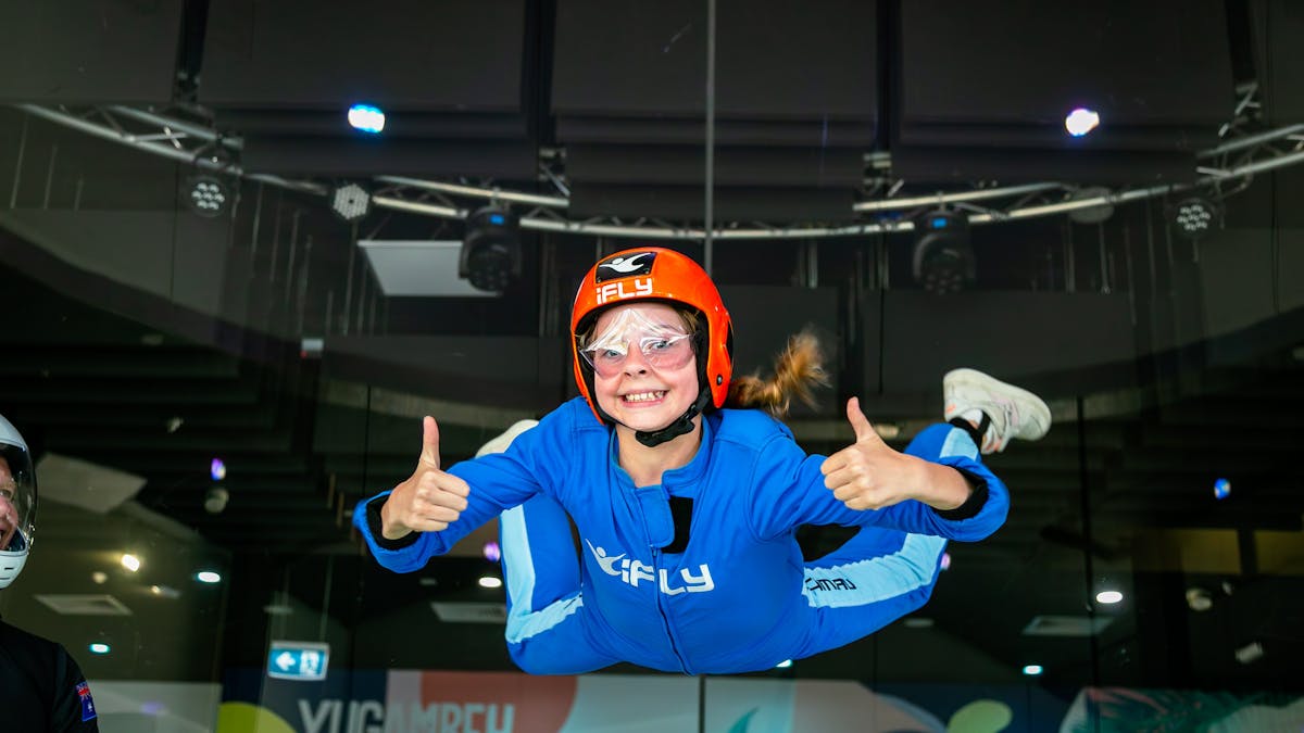 Young girls gives the thumbs up while flying for the first time.